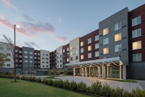 A modern multi-story hotel with a covered entrance and a landscaped courtyard.