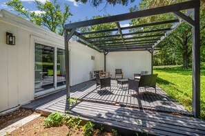 Eine überdachte Terrasse mit Gartenmöbeln und einer Pergola.