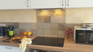 A kitchen with a Bosch coffee maker, a Proline microwave, a cutting board, and a bowl of oranges. - Charming apartment with a panoramic view of the sea. 5 minutes from the beaches (Valle-di-Campoloro)