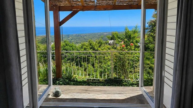A balcony with a view of the ocean, a pergola, and a metal railing. - Charming apartment with a panoramic view of the sea. 5 minutes from the beaches (Valle-di-Campoloro)