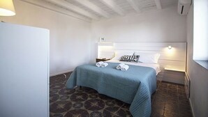 Una camera da letto con un letto, un comodino, una lampada a muro e un pavimento a motivi.