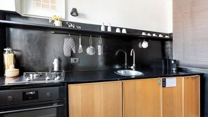 Una cucina con piano di lavoro nero, mobili in legno, lavandino in acciaio inossidabile e diversi utensili da cucina appesi sopra il lavandino.