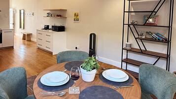 A dining area with a round table set for two, surrounded by teal chairs.