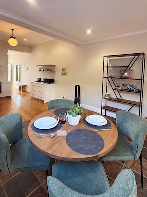 A dining area with a round table set for two, surrounded by teal chairs.