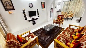 A living room with a TV, sofa, coffee table, and dining area.
