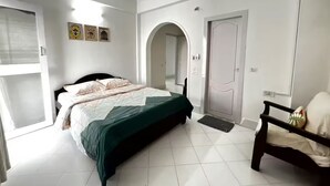 A bedroom with a bed, a chair, a door, and a window.