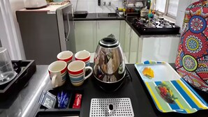 A compact kitchen with a gas stove, a kettle, and a tray with utensils.