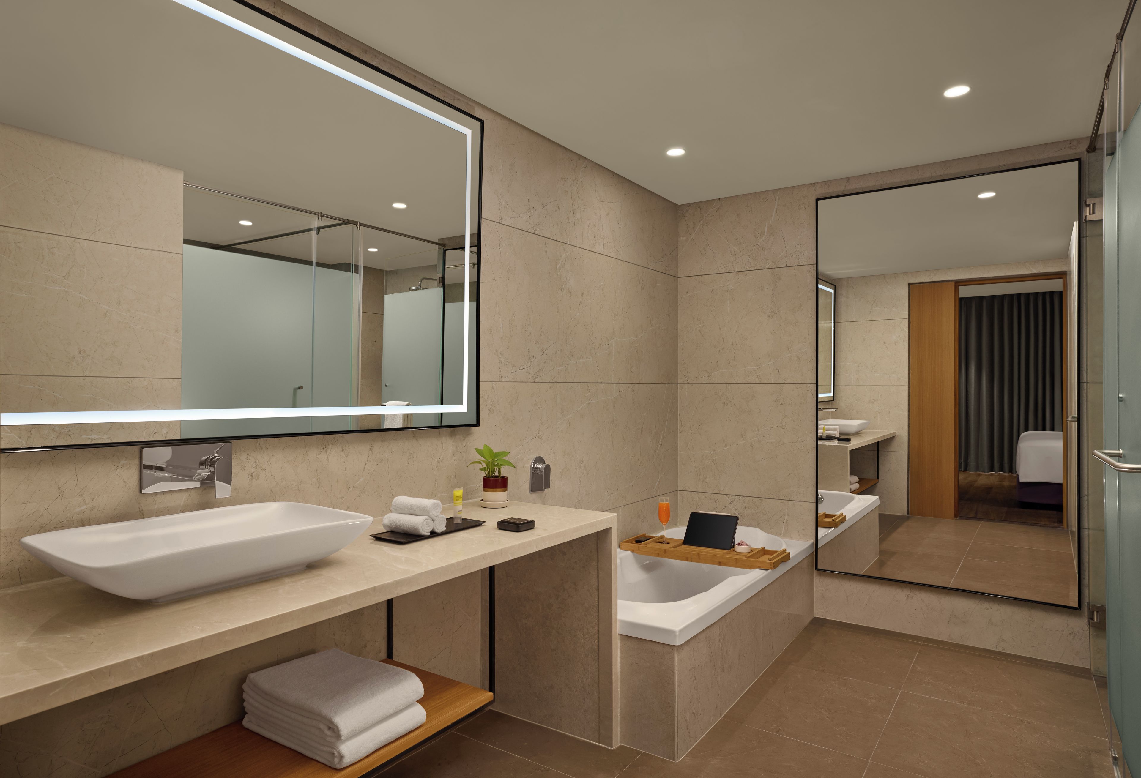 A modern bathroom with a large mirror, a vessel sink, and a separate bathtub.