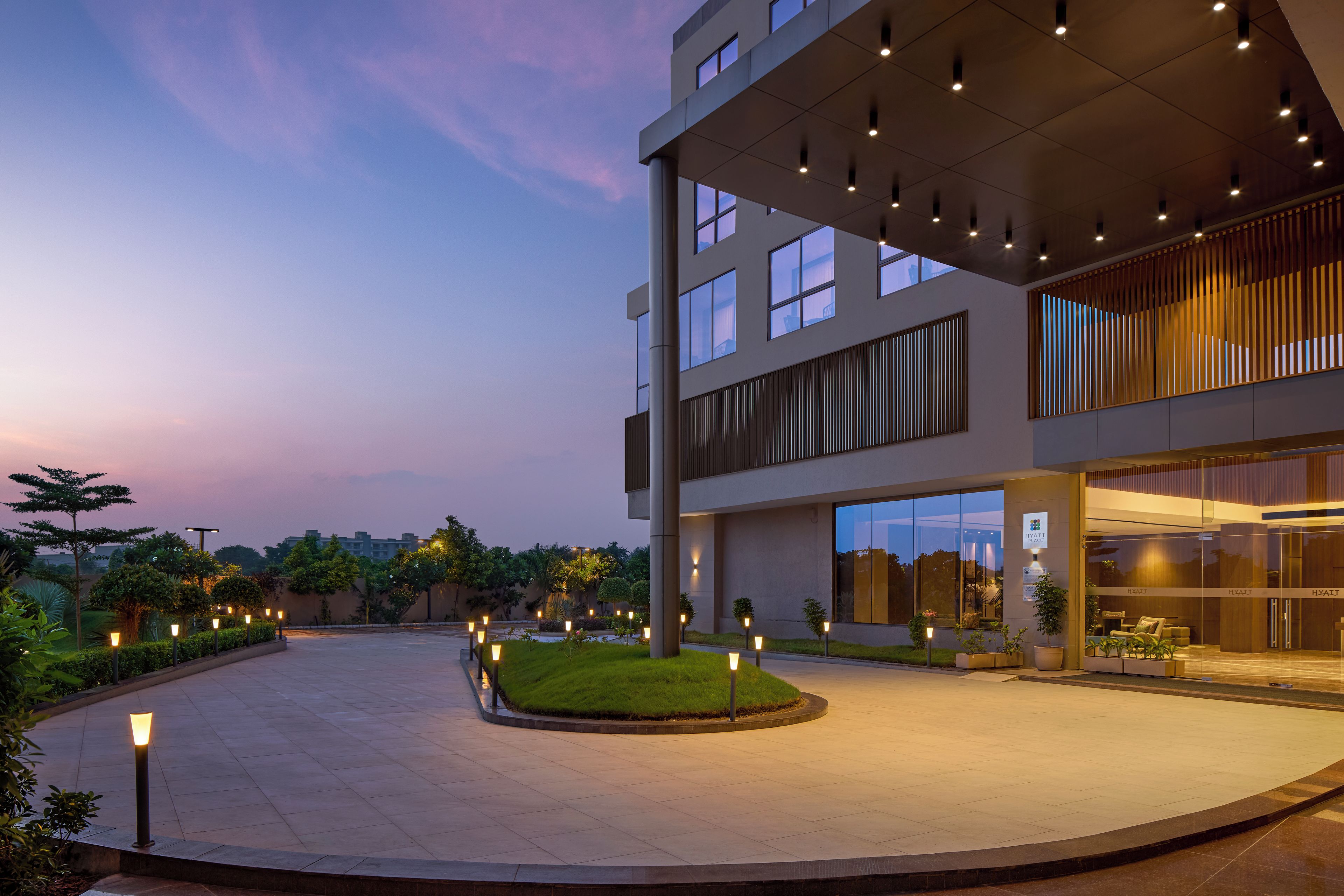 A modern building with a large glass entrance, a landscaped courtyard, and outdoor seating area.