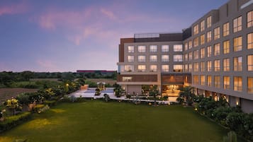 A modern hotel with multiple floors, a well-maintained lawn, and a landscaped garden.