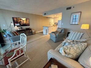 Ein Wohnzimmer mit einer Couch, einem Sessel und einem Fernseher an der Wand.