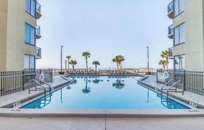 Ein Pool mit Blick auf Palmen und ein Gebäude mit Balkonen.