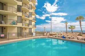 Um hotel com piscina, espreguiçadeiras e vista para o oceano.