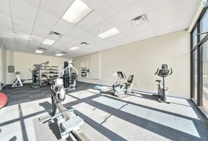 Ein Fitnessstudio mit verschiedenen Trainingsgeräten, darunter Laufbänder, Ergometer und Kraftgeräte.