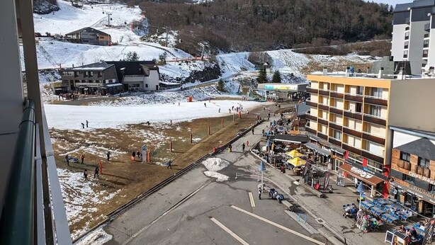 Une vue d’un parking avec une montagne en arrière-plan, un immeuble à plusieurs étages et un restaurant doté d’une terrasse.