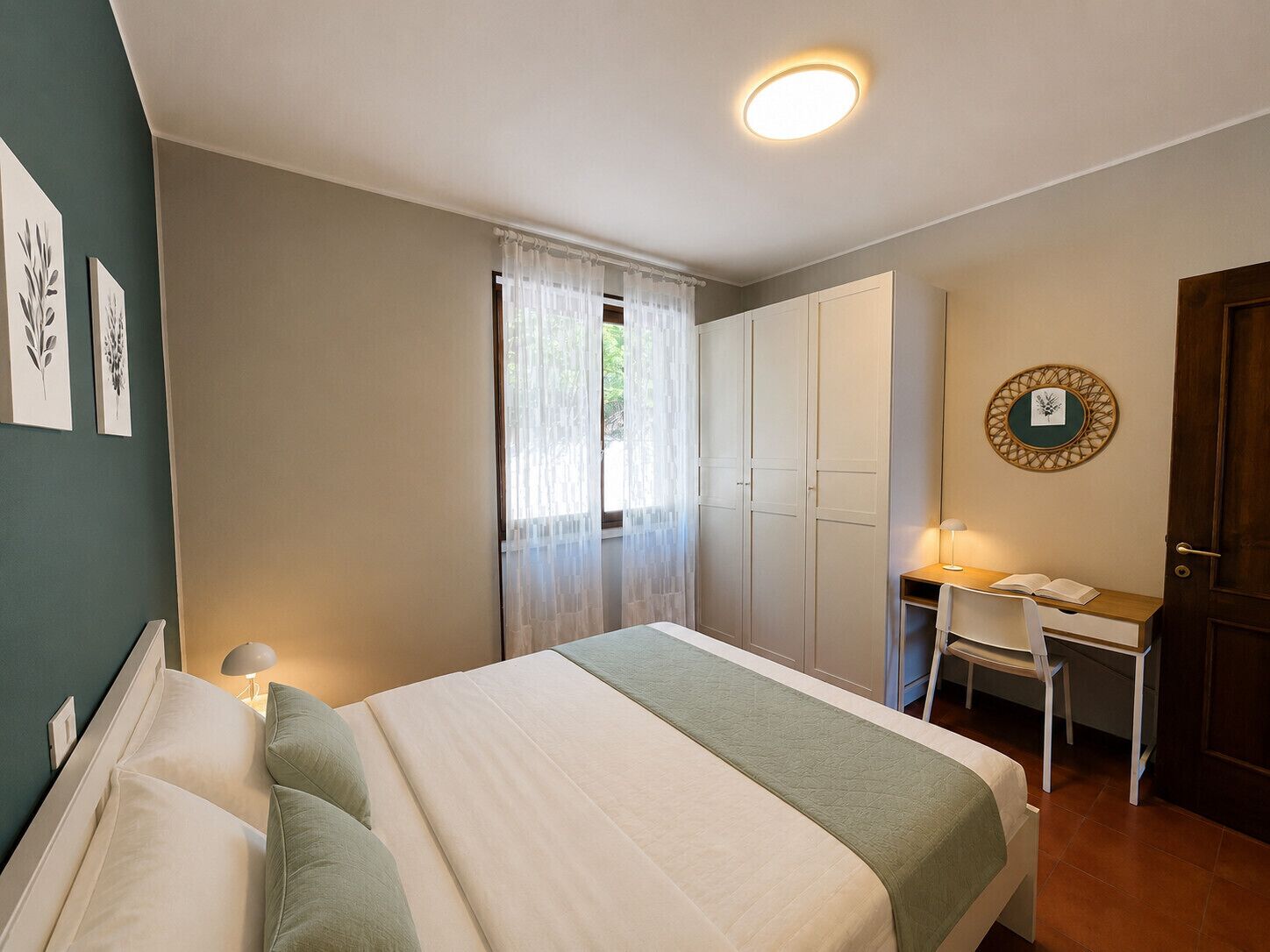A bedroom with a bed, a desk, and a wardrobe.