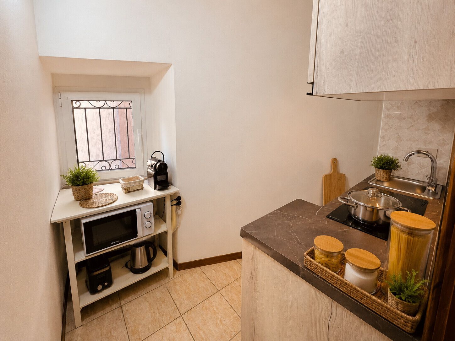 A compact kitchen with a microwave, kettle, and small sink.