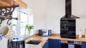 Una cocina moderna con encimeras de madera, estufa negra, microondas y hervidor.