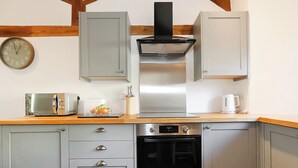Een keuken met een broodrooster, waterkoker, oven en een klok aan de muur.