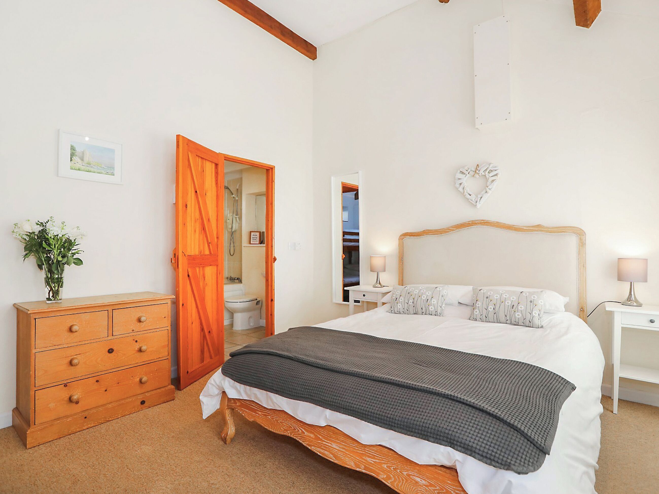 Un dormitorio con cama, cómoda y puerta abierta que da a un baño.
