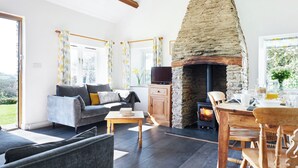 En stue med en stenspir, en sofa, et fjernsyn og et spisebord med stole.