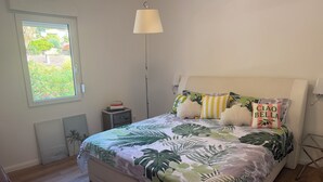 Un dormitorio con cama, mesita de noche, lámpara y ventana.