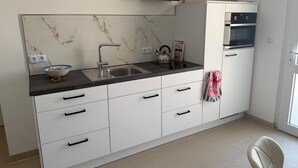 Una cocina moderna con salpicadero de mármol, horno empotrado y un lavamanos.