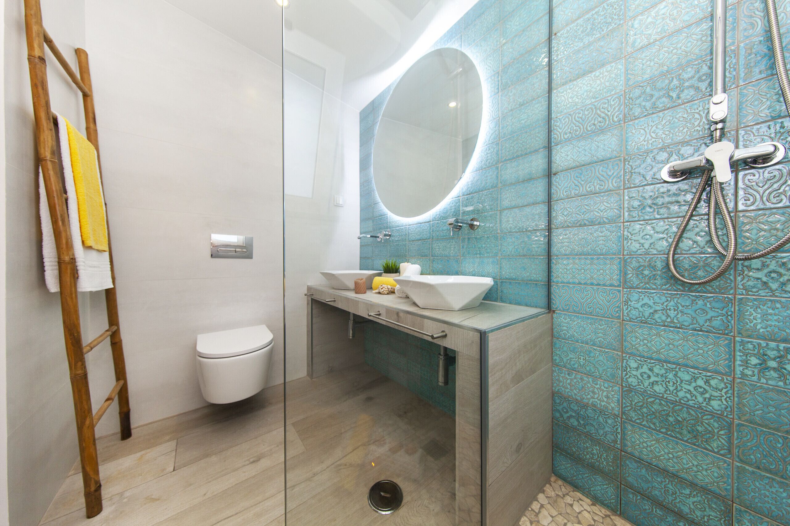 Un bagno moderno con cabina doccia in vetro, un water, un mobile lavabo con specchio e un porta asciugamani.