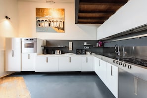 A modern kitchen with white cabinets, a built-in oven, a coffee maker, and a stainless steel range hood. - Isrotel Tower by Sea N' Rent (Tel Aviv-Yafo)
