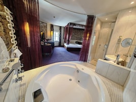 A modern bathroom with a large bathtub, a separate shower area, and a vanity with a mirror.