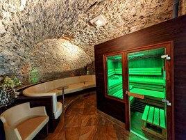 Zona de spa con pared de piedra, banca de madera y sauna con paredes de vidrio.