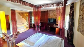 A hotel room with a bed, a desk, a TV, and a bathroom with a bathtub. - Hotel Öhlknechthof (Horn)