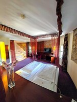 A hotel room with a bed, a desk, a TV, and a bathroom with a bathtub.