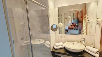 Un bagno moderno con cabina doccia in vetro, lavabo doppio e un grande specchio.