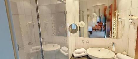 Un baño moderno con cabina de ducha de vidrio, tocador doble y un espejo grande.