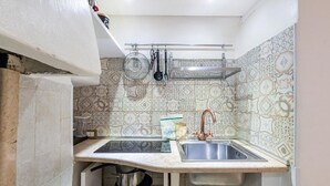 Una cucina compatta con due lavelli, un porta pentole a sospensione e piastrelle decorative a parete.