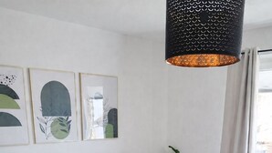 A bedroom with a large bed, a hanging light fixture, a potted plant, and artwork on the wall.