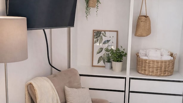 A modern living room with a sofa, a flat-screen TV, a lamp, and a bookshelf.