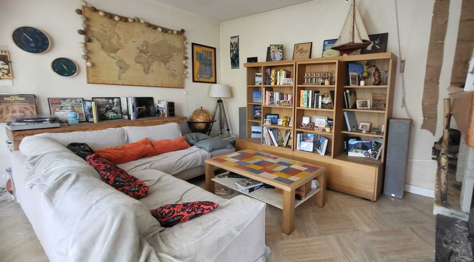 Una sala de estar con un sofá, una mesa de centro, una estantería, un globo terráqueo y un mapa mundial en la pared.