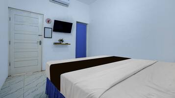 Una habitación con cama, puerta, televisor montado en la pared y un pequeño estante con una planta.