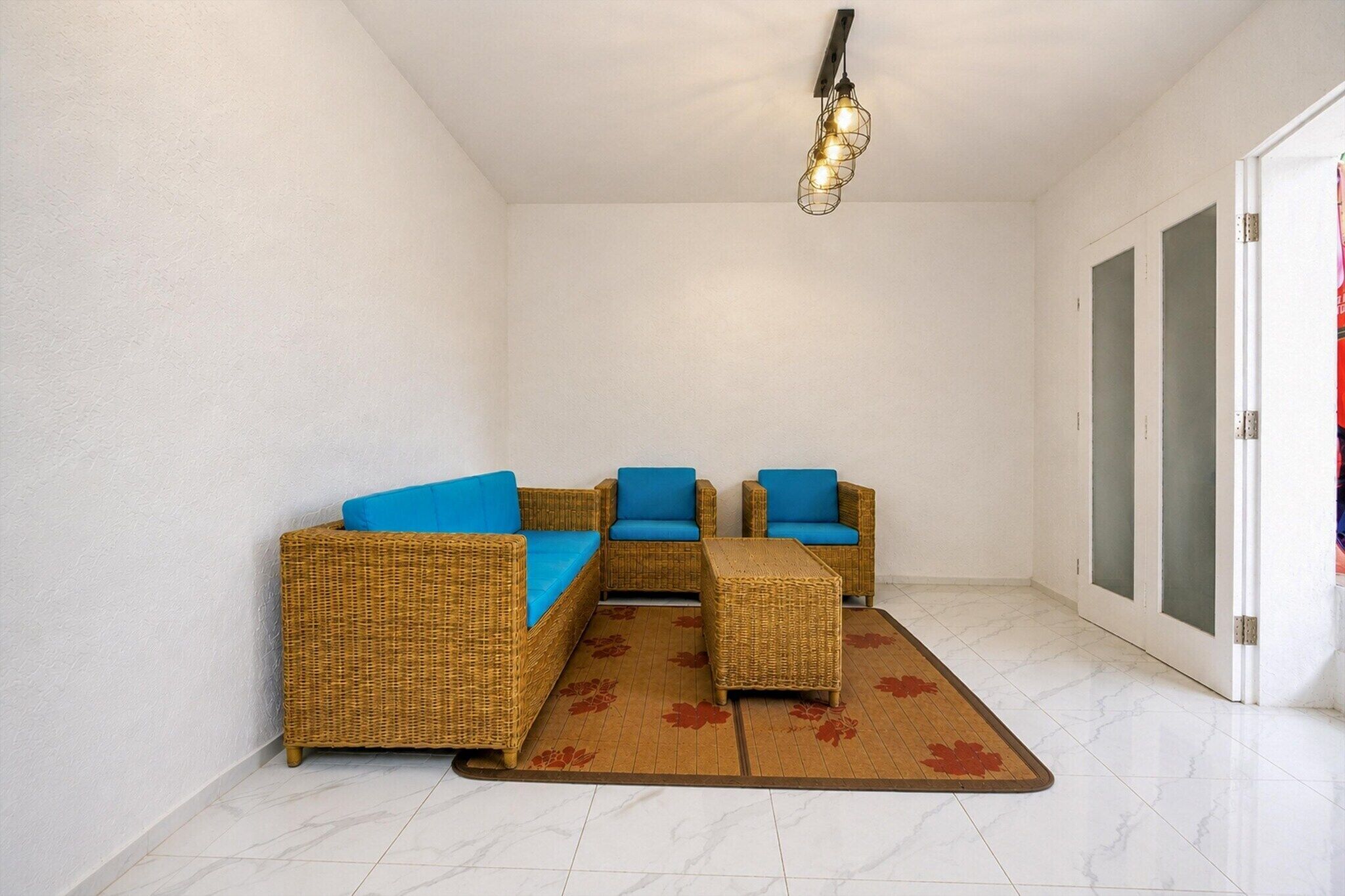A room with wicker furniture, a ceiling light, and a door.