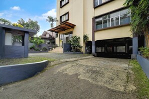 A modern building with a covered entrance, a courtyard with plants, and a paved walkway.