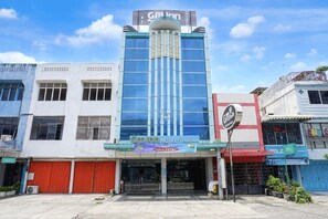A hotel with a prominent sign, a glass facade, and a red entrance.