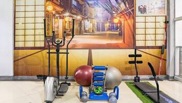 Ein Fitnessraum mit Trainingsgeräten, einer Tatami-Matte und einer traditionellen japanischen Wandmalerei.