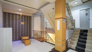 Un intérieur moderne avec un escalier, une colonne en bois et un mur orné de motifs.