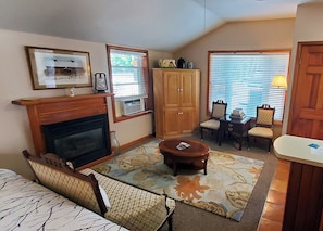 Ein Wohnzimmer mit Kamin, einer Couch, einem Couchtisch, einem Esstisch mit Stühlen und einem Fenster mit Jalousien.