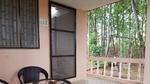 Un balcon avec une porte vitrée, une table ronde avec des chaises et une vue sur les arbres.