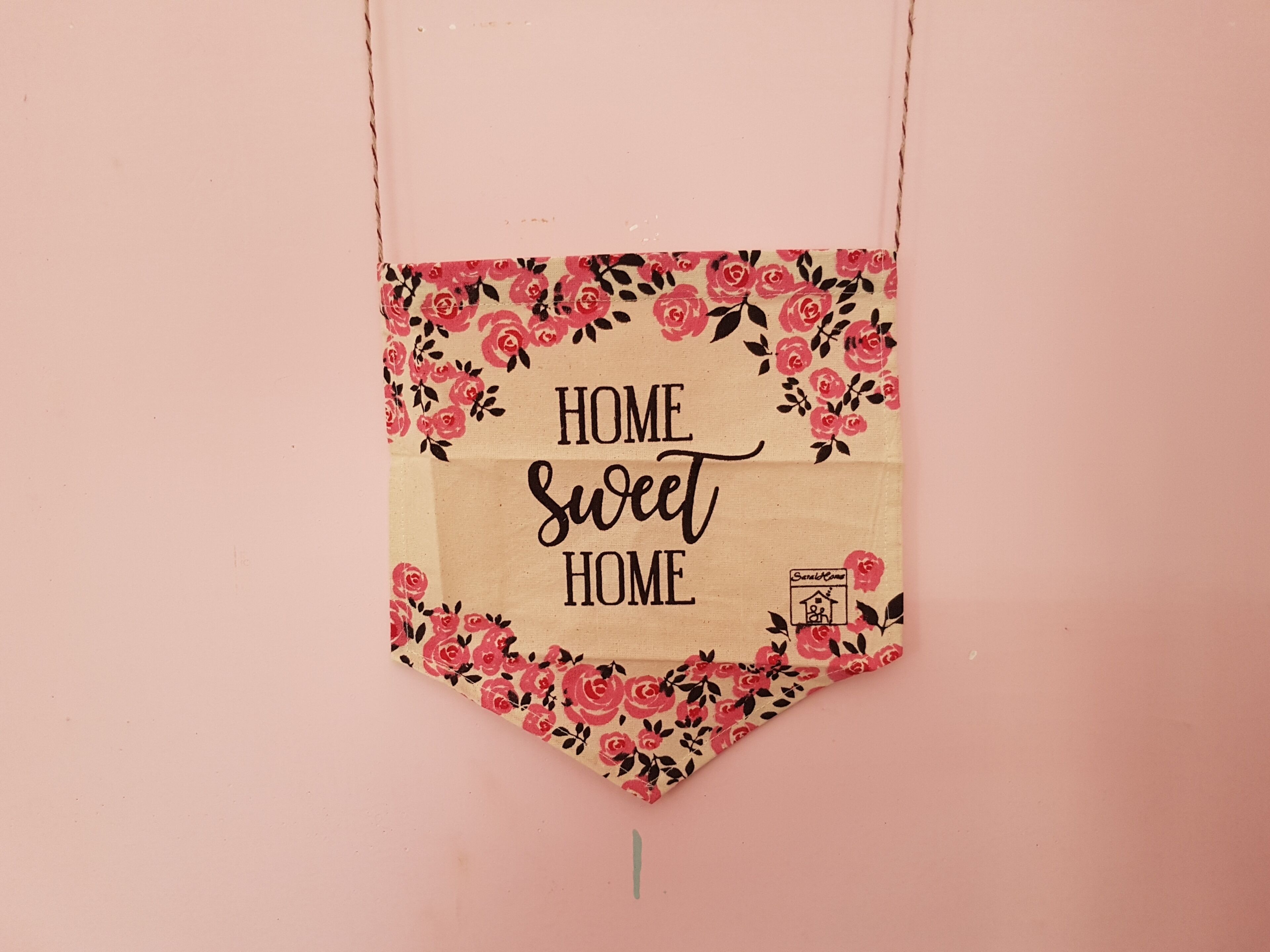 Un letrero colgante con el texto 'HOME Sweet HOME' rodeado de un diseño floral.