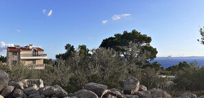 A building with a red roof, surrounded by trees and rocks. - 2-Story Stone House in Bonaca - Ocean View & Privacy (Baška Voda)