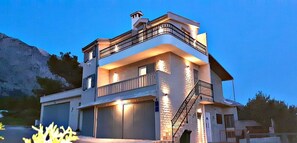 Ein mehrstöckiges Gebäude mit Balkon, Treppe und Garage.